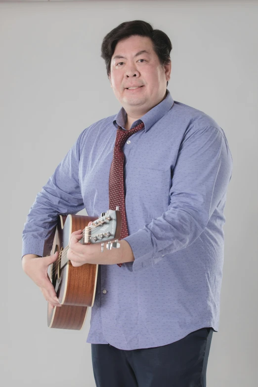 a man in a tie and shirt playing an ukulele