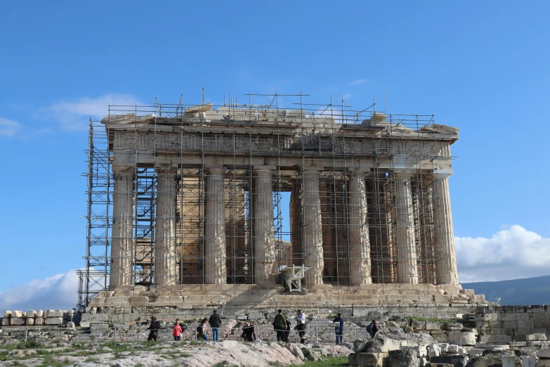 a group of people standing in front of the part of a temple with scaffolding