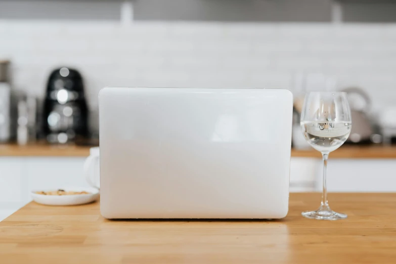 a glass of white wine sitting on a kitchen counter