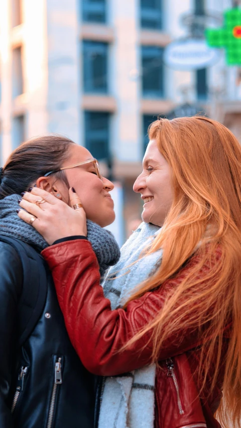 two women are emcing each other with a building in the background