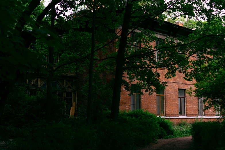 the back side of an old red brick building with lots of trees