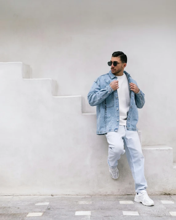 a man sitting on top of some stairs wearing a denim jacket