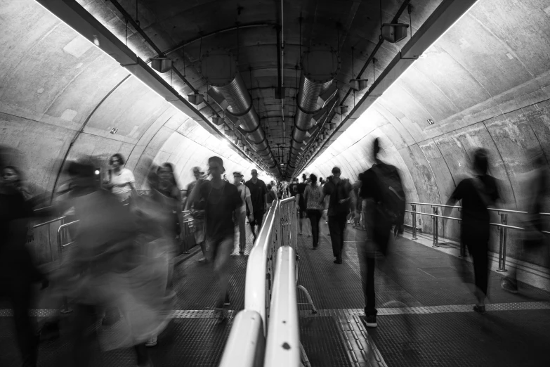 black and white image of people moving down a subway
