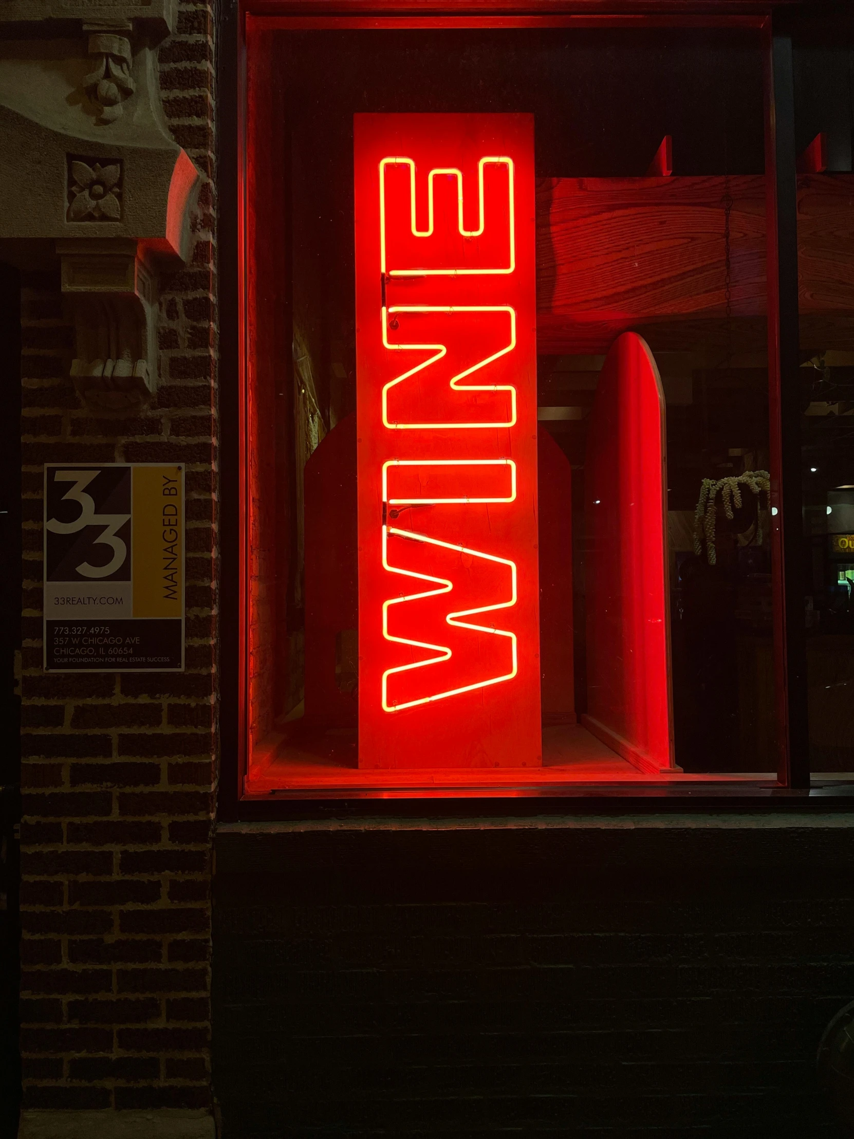 a red neon sign inside a window on a dark street