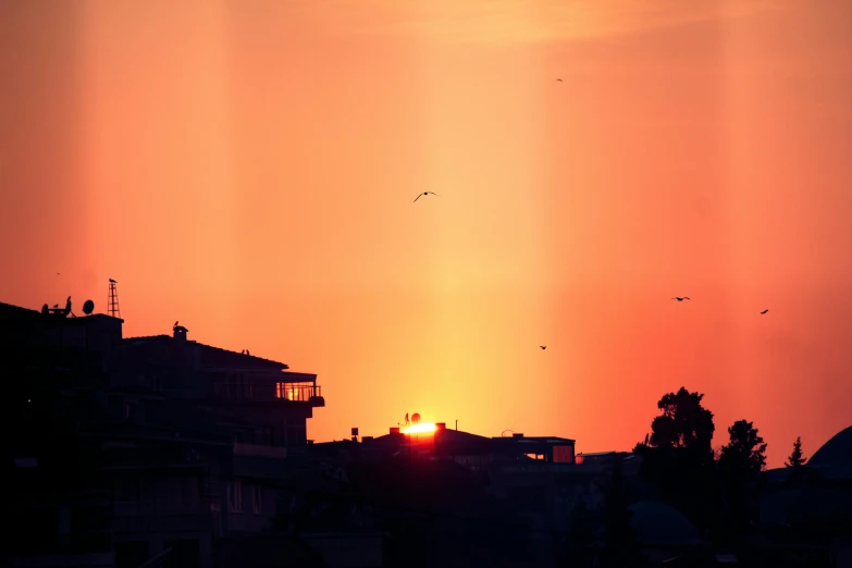 the sun is rising over buildings in an urban area