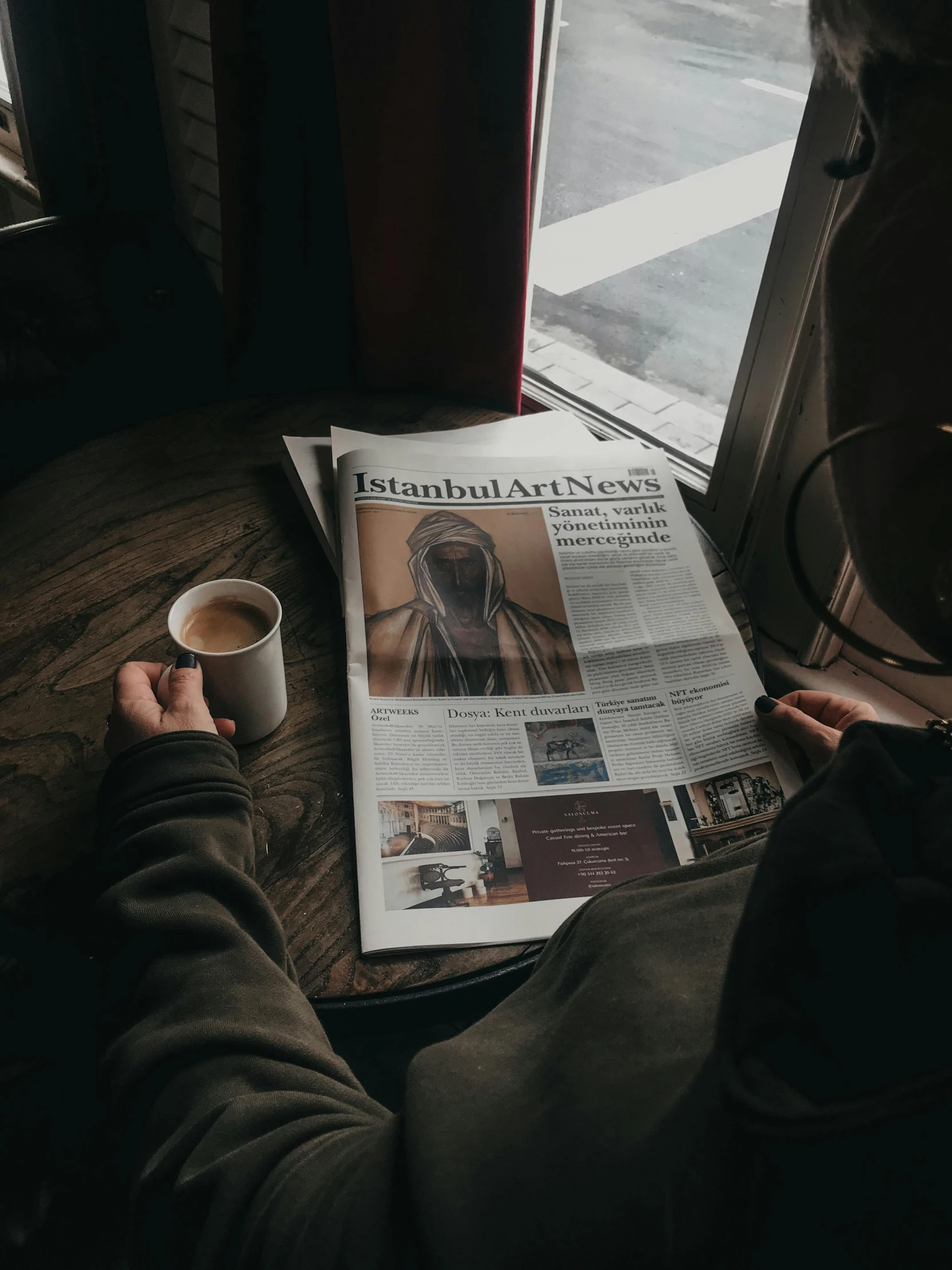 someone is reading a newspaper with a cup of coffee