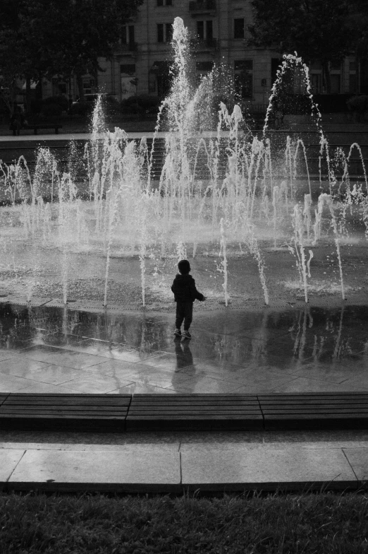 a boy walking in front of a fountain