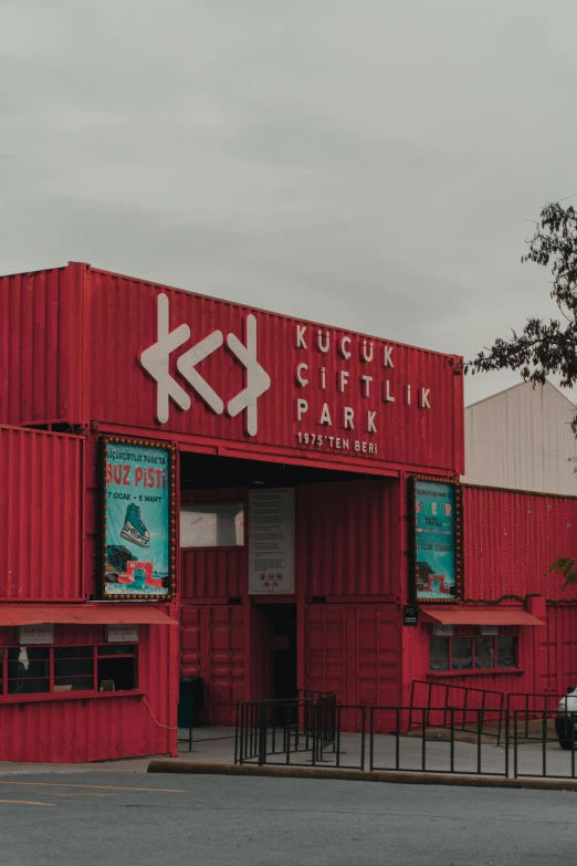 a building with red containers and a gate on one side