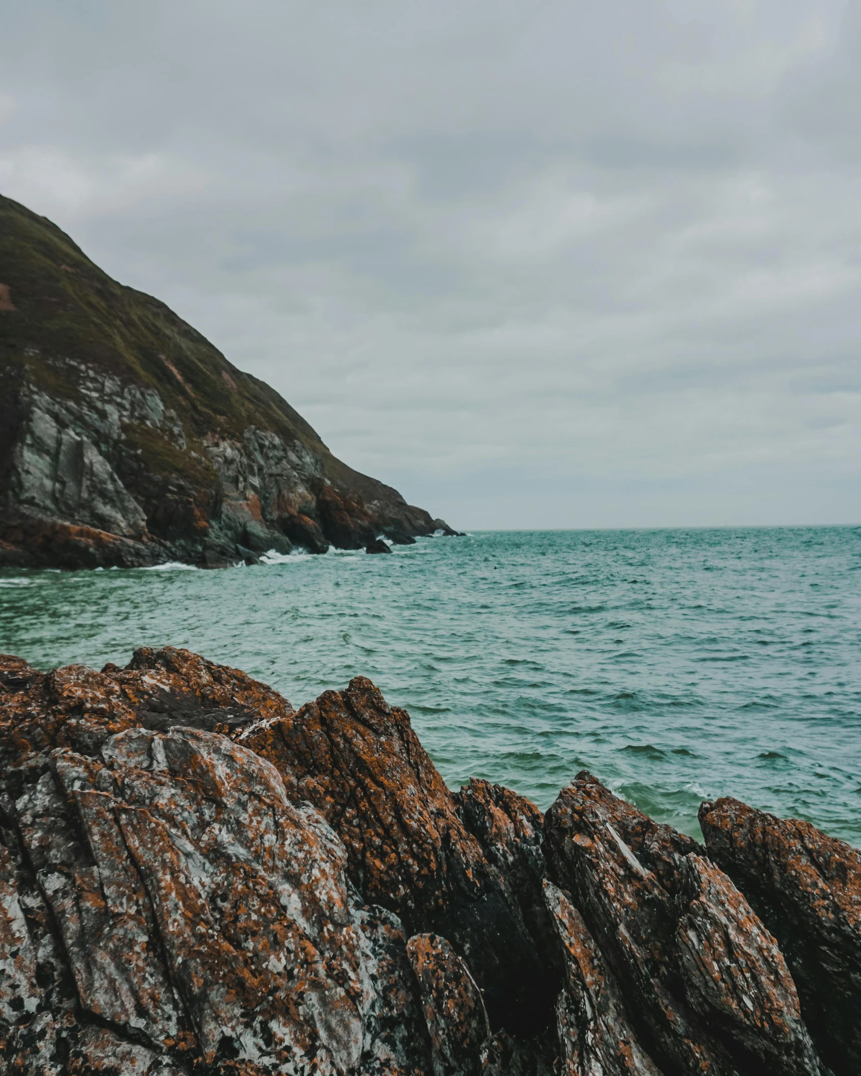 there is a person standing on the rocks by the ocean