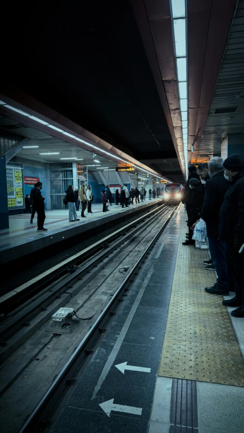 people standing in line waiting on a subway platform