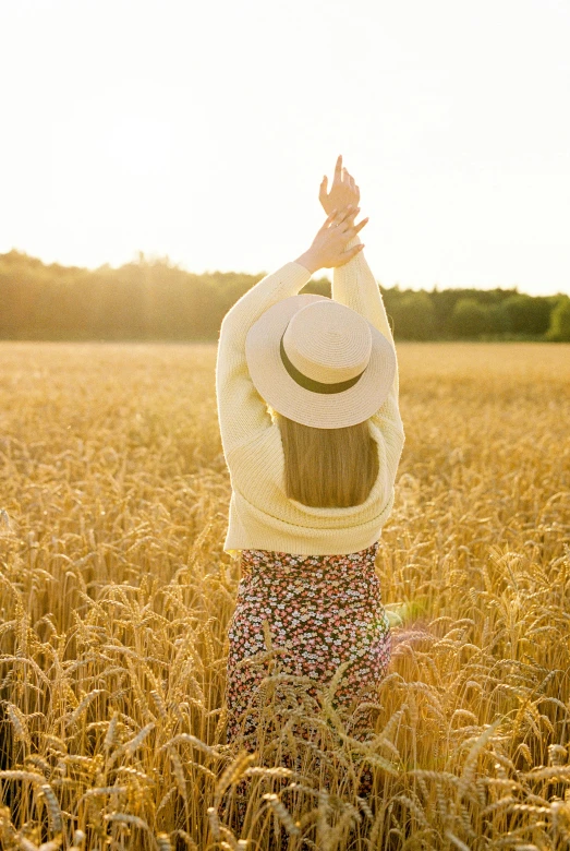 a woman with her arms stretched up in the middle of a field