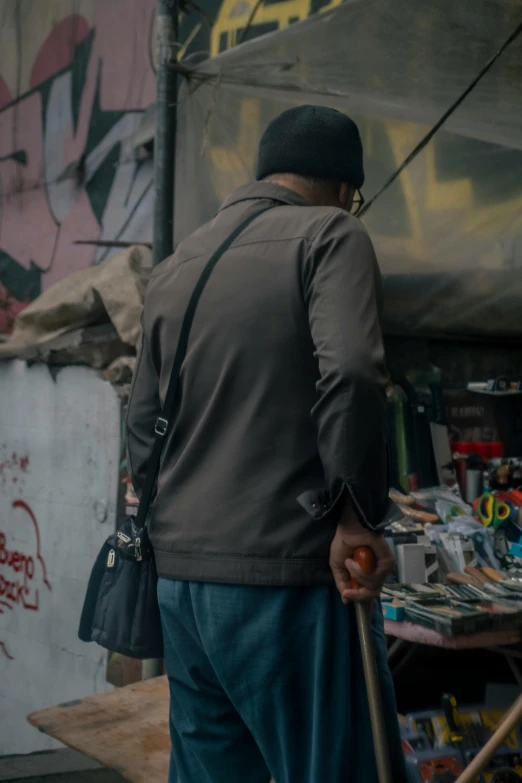 a man holds a stick while standing near a storefront