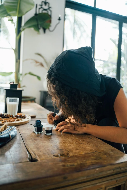 an attractive woman sitting at a wooden table with various items