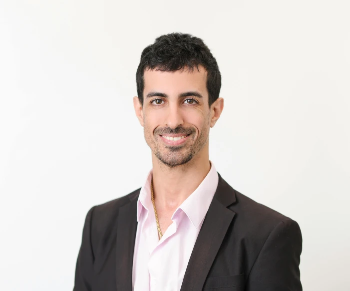 a man smiling at the camera in front of a white background