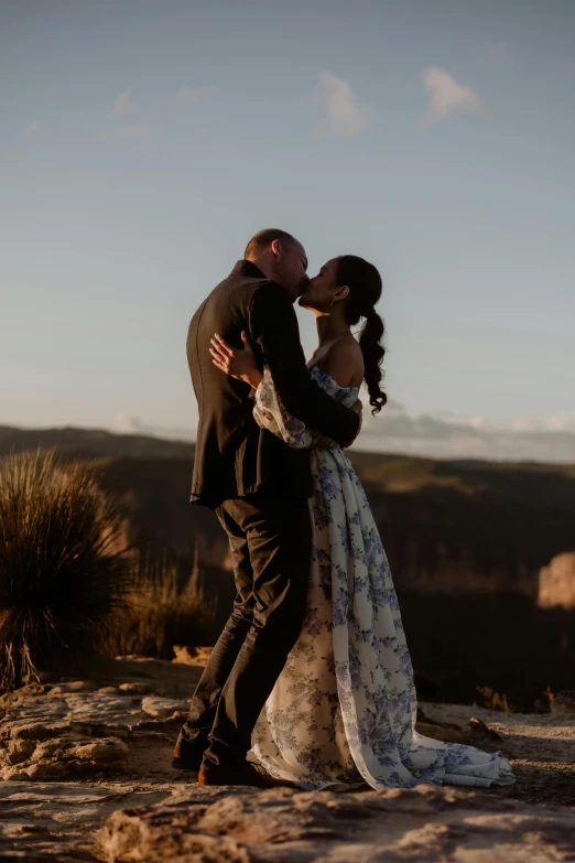 a man and a woman kissing on top of a mountain