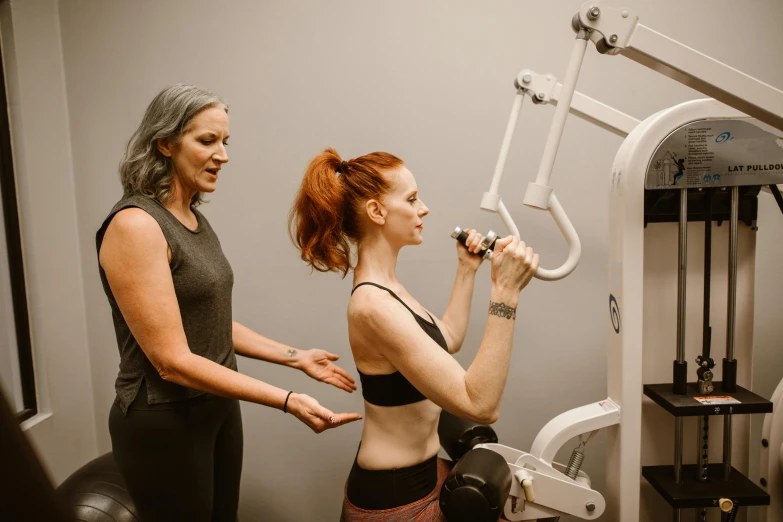 two woman stand in front of an exercise machine