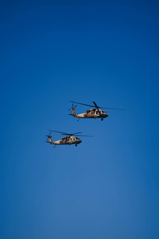 two military helicopters flying close to each other