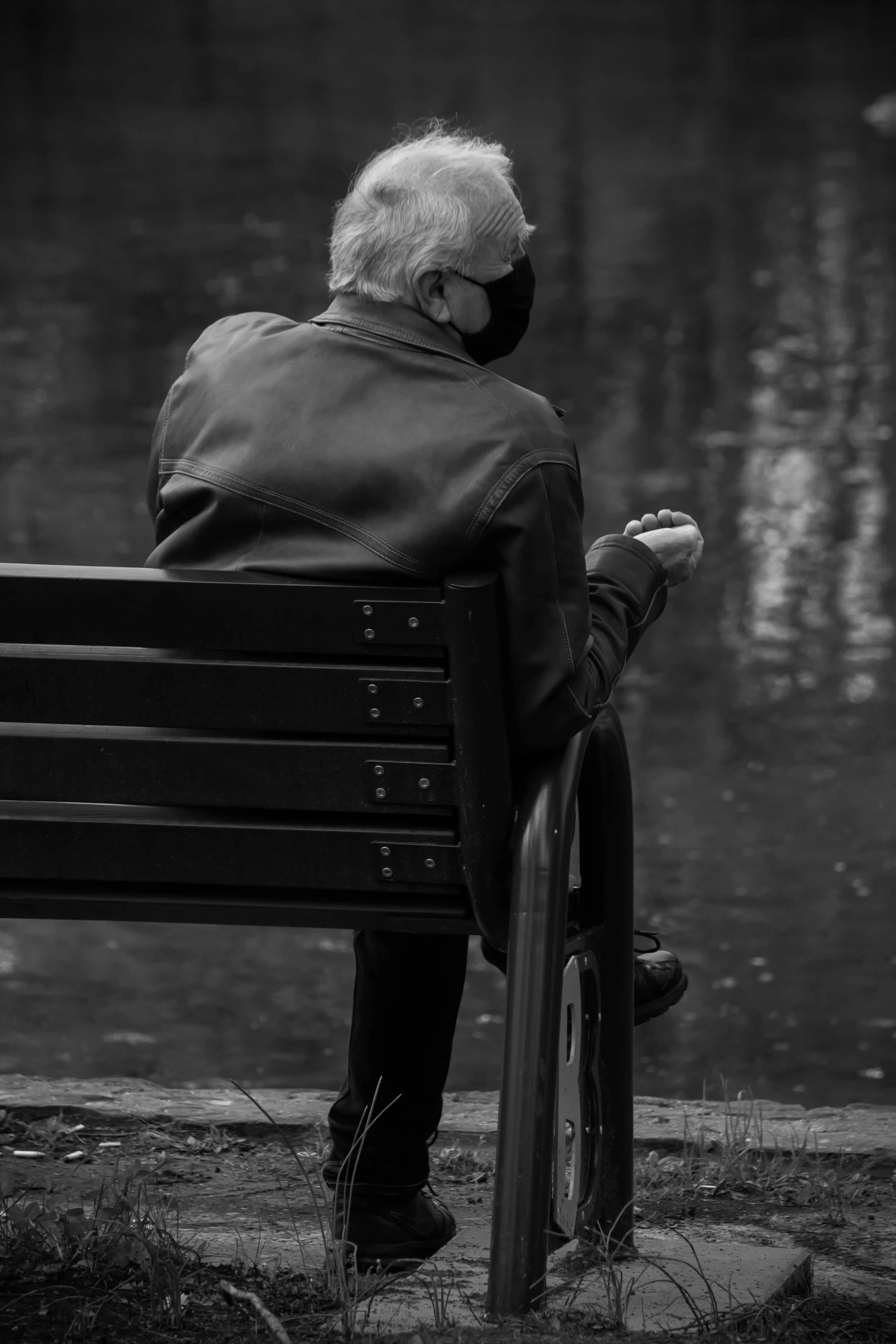 a person with glasses sitting on a bench next to a body of water