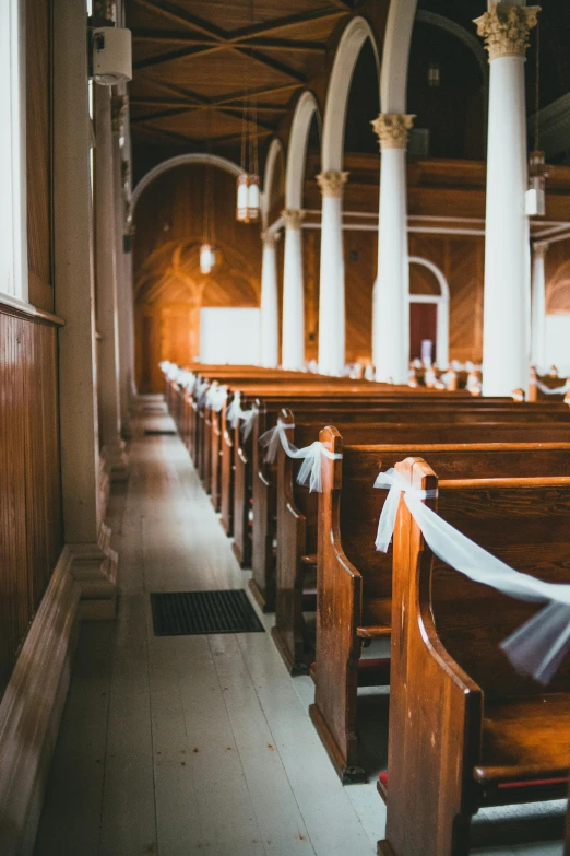 a dimly lit church with pews with a sheer ribbon on the alter