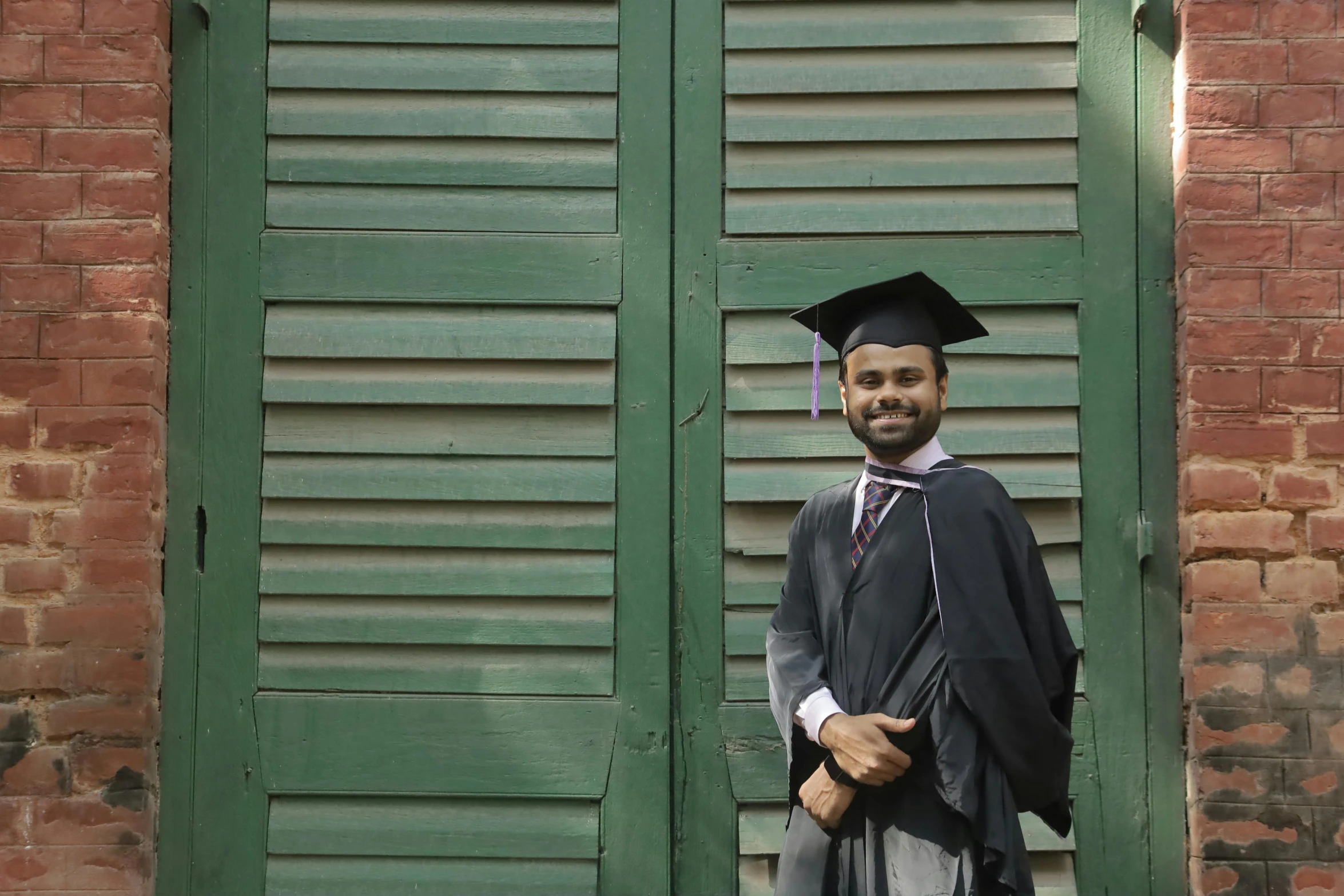 a man wearing a graduation cap and gown poses for a picture