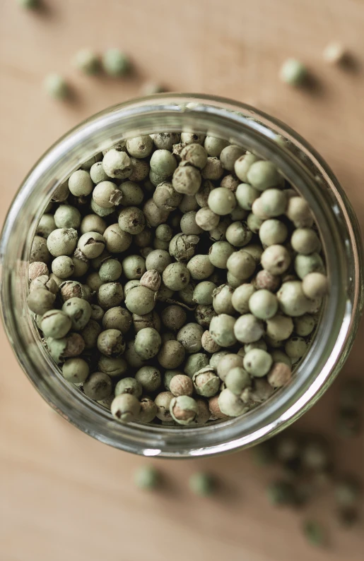 green pea pods are packed into a glass jar