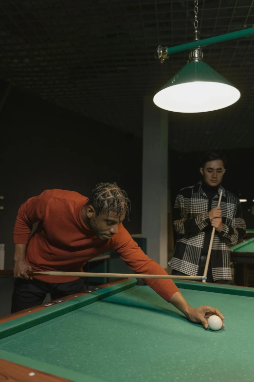 two men playing pool with a green table cloth