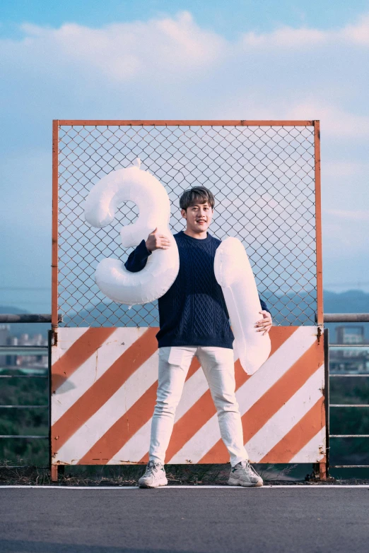 man standing behind a net holding several large doughnuts