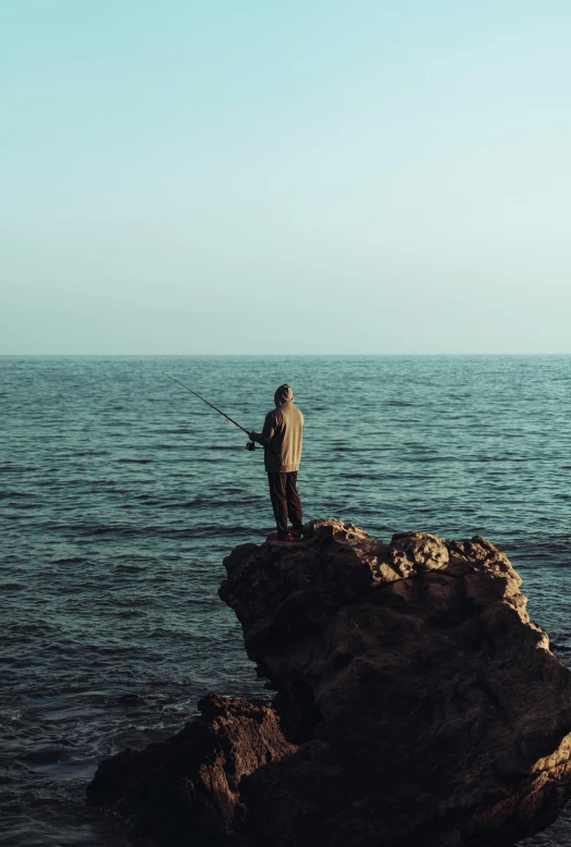 a man is standing at the edge of a cliff fishing