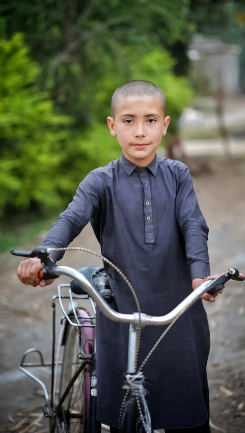 a  stands next to a bike on dirt