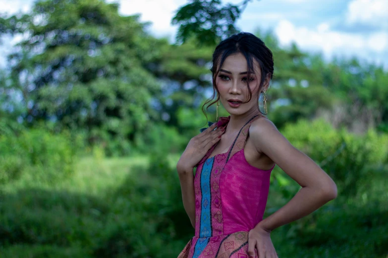 a young woman standing in a field with her hands on her hips