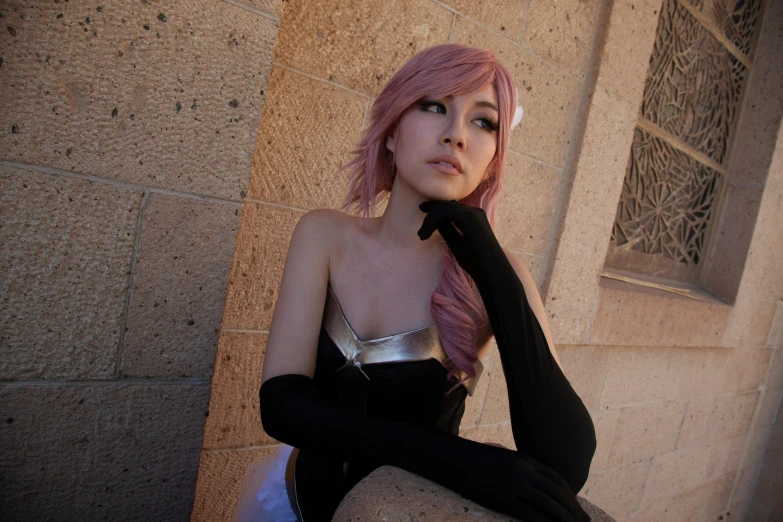 woman with pink hair and silver dress leaning against concrete wall