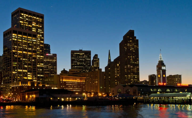 a city lit up with tall buildings and water