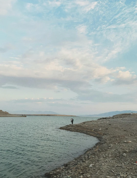 an image of a man standing on the water with mountains in the background