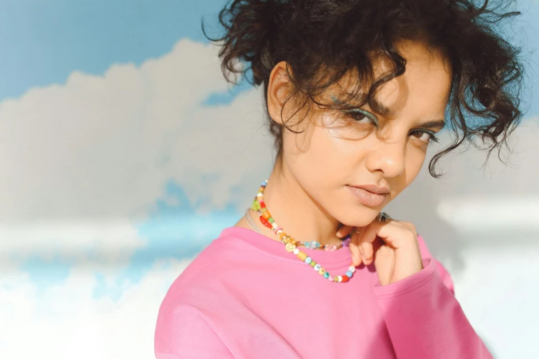 a woman with curly hair wearing a bright necklace