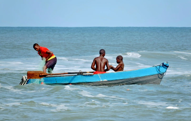 three men standing on the bow of a boat in an ocean