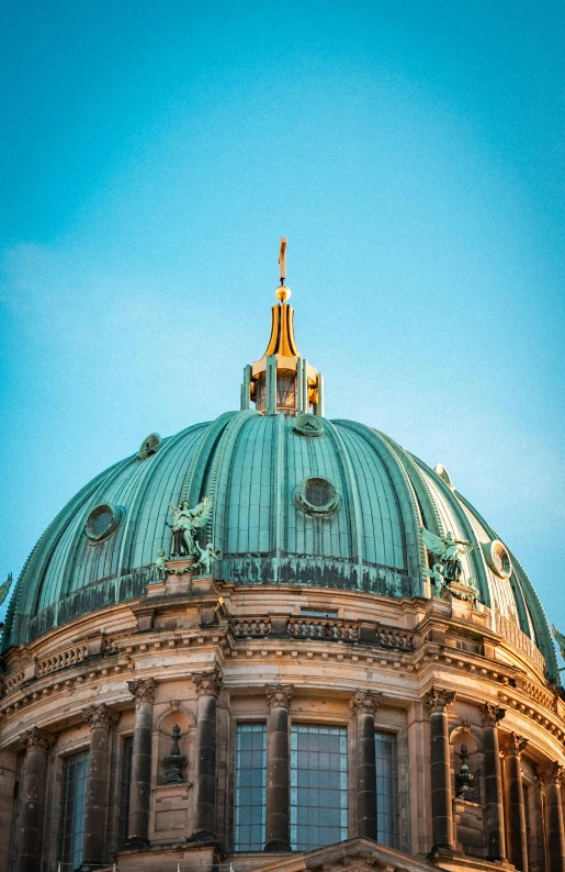 a large green dome with blue sky and light clouds in background