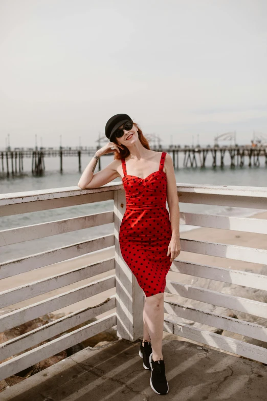 a woman in a dress standing near a dock