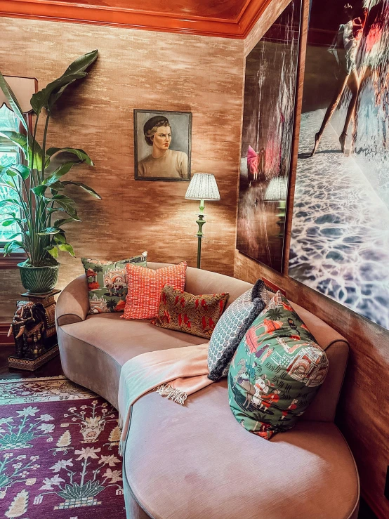 a pink couch, mirror and potted plant in the corner of a room