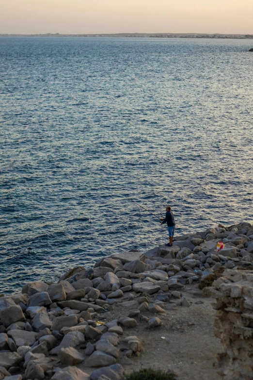 a person stands on rocks near the water