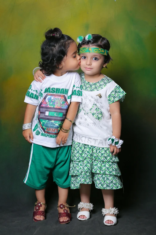 two little girls that are standing in front of a green backdrop