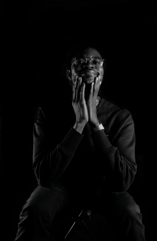 black and white pograph of a person seated with their hands together