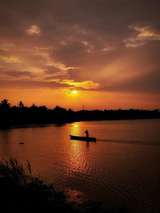 person paddling a boat at sunset on water