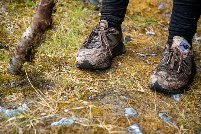 a person wearing dirty shoes standing in the grass