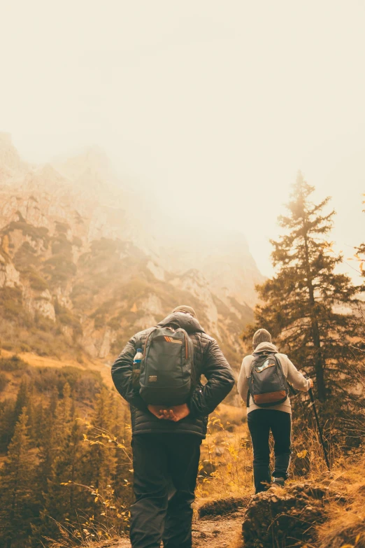 two people with back packs are hiking in the mountains