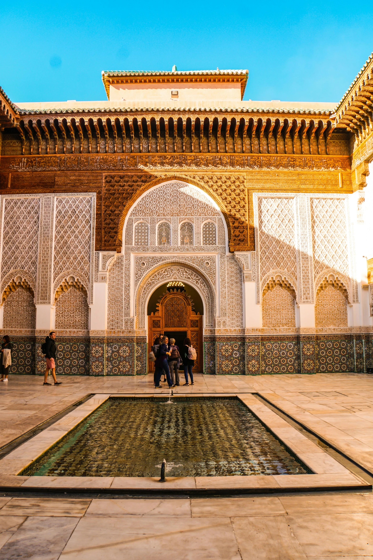 many people stand around the courtyard of a white and blue building