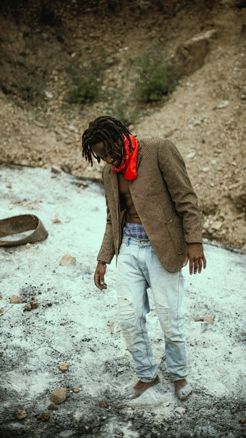 a man walking in the snow wearing a jacket and red scarf