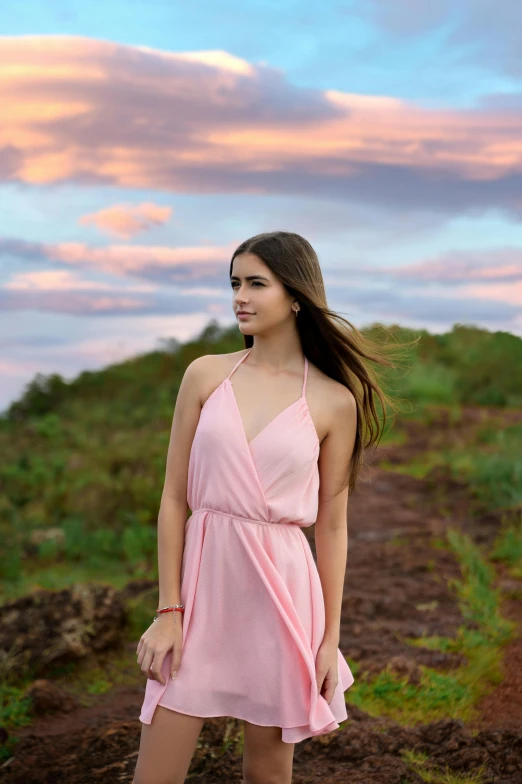 a beautiful young woman standing on a dirt path