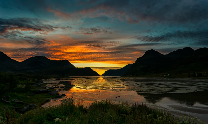 a lake with mountains in the background that have been bathed by sun