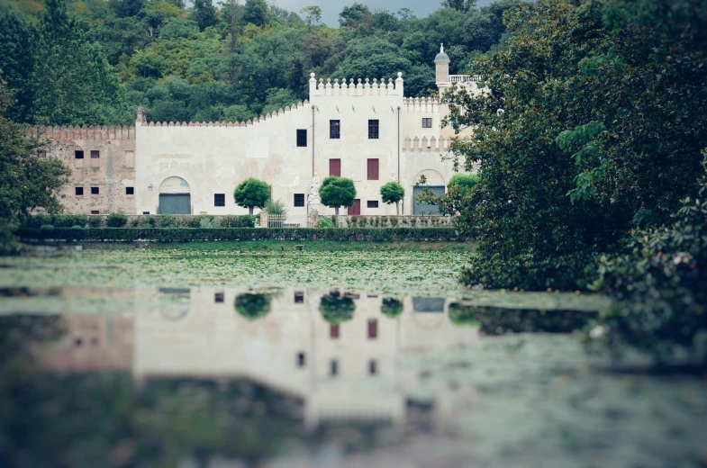a castle like structure reflected in the water near a forest