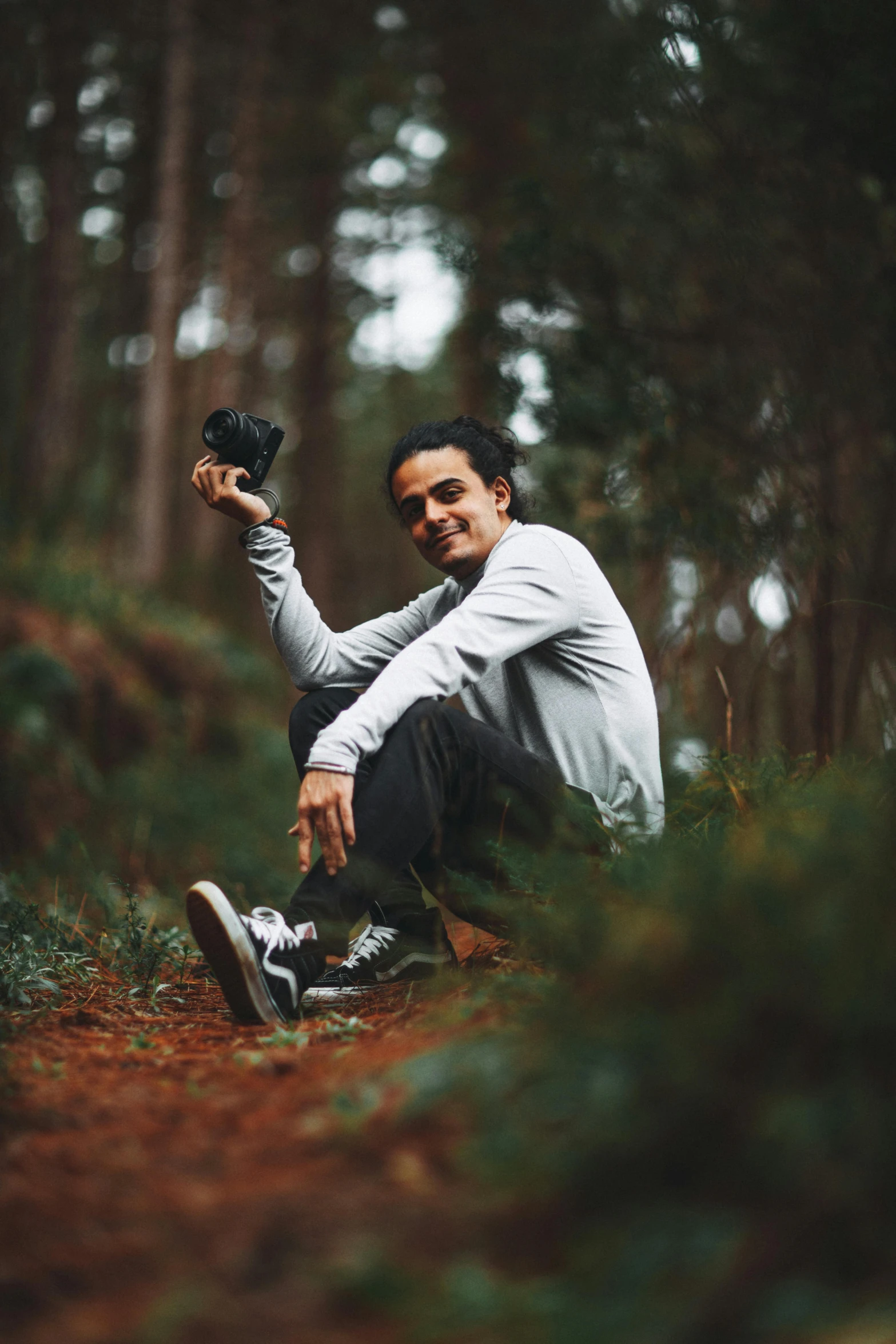 a man squats in the woods holding soing